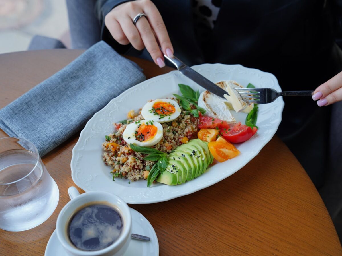 A delicious and healthy breakfast featuring avocado, eggs, and coffee served on a wooden table.